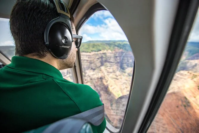 A passenger wearing a headset looking out of a cabin window